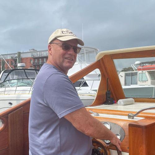 Jim behind wheel of boat in harbor